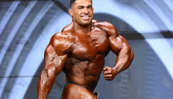 Derek Lunsford durante sua participação no Olympia 2025
             -       
        Jeff Binns/NPC News Online