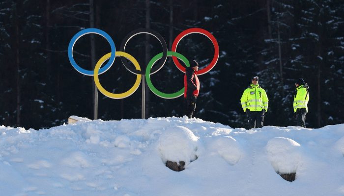 Seguranças ao lado de anéis olímpicos em Tesero, na Itália, onde acontecerão as provas de esqui cross-country dos Jogos de Inverno 
             -       
        Kai Pfaffenbach - 3.fev.2026/Reuters