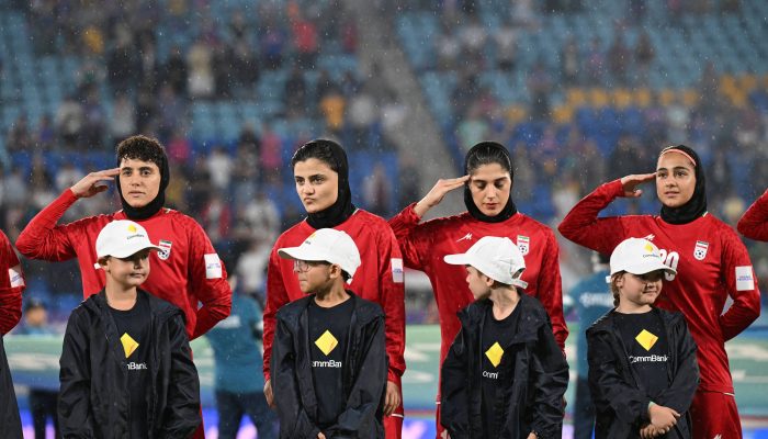 Jogadoras da seleção iraniana prestam continência antes de duelo contra as Filipinas no Gold Coast Stadium, na Austrália 
             -       
        Dave Hunt - 8.mar.26/AAP Image via Reuters