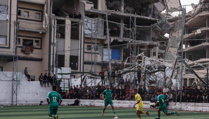 Palestinos assistem a um jogo de futebol entre os destroços de prédios na Faixa de Gaza destruídos pelas forças de Israel no combate com o Hamas
             -       
        Omar Al-Qattaa - 9.fev.26/AFP