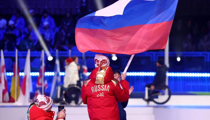 Os porta-bandeiras Ivan Golubkov e Varvara Voronchikhina, da Rússia, desfilam durante a cerimônia de encerramento dos Jogos Paralímpicos de Milão-Cortina 2026
             -       
        Lisi Niesner-15.mar.2026/Reuters