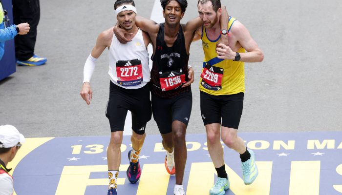 Robson de Oliveira (de branco) e o norte-irlandês Aaron Beggs (de amarelo) auxiliam o americano Ajay Haridasse na Maratona de Boston 
             -       
        CJ Gunther - 20.abr.26/Reuters
