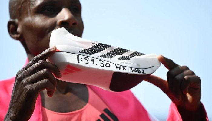O corredor Sabastian Sawe, do Quênia, posa com o tênis que usou para quebrar o recorde da Maratona de Londres, com o tempo anotado na sola
             -       
        Justin Tallis - 26.abr.26/AFP