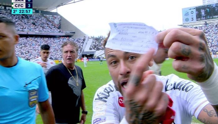 Neymar exibe para câmera um papel com o número correta da substituição indicada pelo Santos
             -       
        Reprodução/Premiere